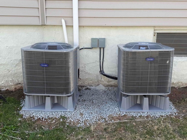 Two newly installed Carrier condenser units outside a home